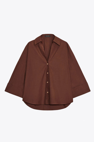 Camisa de fit oversized, manga 3/4 amplia con doblez en puños, cuello camisero, escote v, pinza de amplitud en espalda con trabilla decorativa y bajo curveado. Cierre frontal con hilera de botones en contraste.