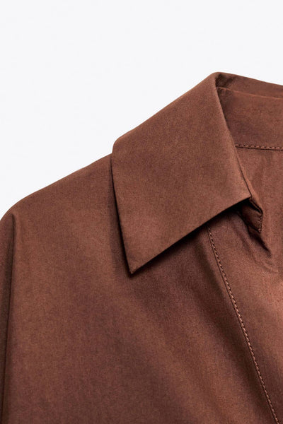 Camisa de fit oversized, manga 3/4 amplia con doblez en puños, cuello camisero, escote v, pinza de amplitud en espalda con trabilla decorativa y bajo curveado. Cierre frontal con hilera de botones en contraste.