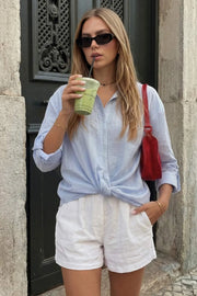 Camisa corta de estampado rayas, fit recto, manga larga rolled up con trabilla ajustable, cuello camisero, cruce frontal con escote v y nudo decorativo en bajo. Detalle de bajo curveado y pinza de amplitud en espalda.