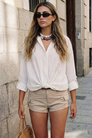 Camisa corta de estampado rayas, fit recto, manga larga rolled up con trabilla ajustable, cuello camisero, cruce frontal con escote v y nudo decorativo en bajo. Detalle de bajo curveado y pinza de amplitud en espalda.