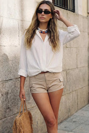 Camisa corta de estampado rayas, fit recto, manga larga rolled up con trabilla ajustable, cuello camisero, cruce frontal con escote v y nudo decorativo en bajo. Detalle de bajo curveado y pinza de amplitud en espalda.