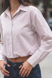 Camisa corta de estampado rayas, cuello camisero, manga larga con puño abotonado, fit abullonado y bolsillo frontal. Cierre frontal con hilera de botones, pinza de amplitud en espalda y rib elástico en bajo.