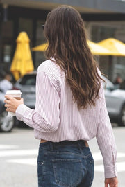 Camisa corta de estampado rayas, cuello camisero, manga larga con puño abotonado, fit abullonado y bolsillo frontal. Cierre frontal con hilera de botones, pinza de amplitud en espalda y rib elástico en bajo.