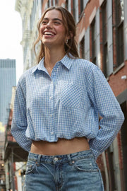 Camisa corta de estampado cuadros, cuello camisero, manga larga con puño abotonado, fit abullonado y bolsillo frontal. Cierre frontal con hilera de botones, pinza de amplitud en espalda y rib elástico en bajo.