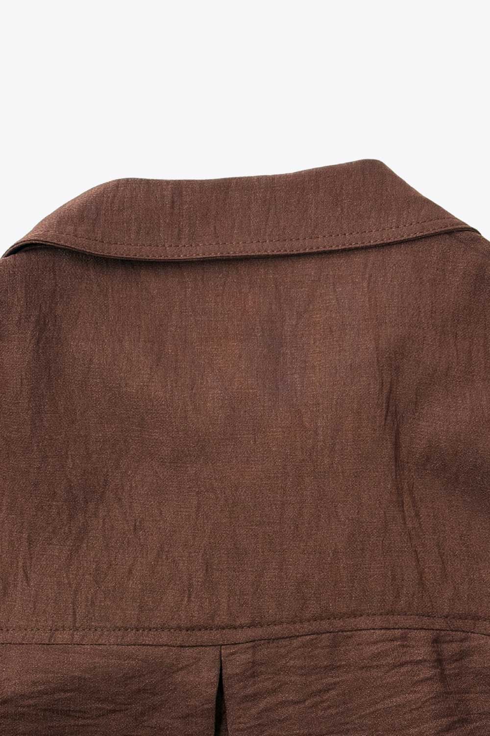 Camisa corta de fit oversized, manga 3/4 amplia con doblez en puños, cuello camisero, bolsillos frontales decorativos con cartera y pinza de amplitud en espalda. Cierre frontal con hilera de botones.