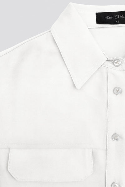 Camisa corta de fit oversized, manga 3/4 amplia con doblez en puños, cuello camisero, bolsillos frontales decorativos con cartera y pinza de amplitud en espalda. Cierre frontal con hilera de botones.