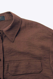 Camisa corta de fit oversized, manga 3/4 amplia con doblez en puños, cuello camisero, bolsillos frontales decorativos con cartera y pinza de amplitud en espalda. Cierre frontal con hilera de botones.