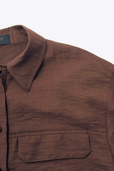 Camisa corta de fit oversized, manga 3/4 amplia con doblez en puños, cuello camisero, bolsillos frontales decorativos con cartera y pinza de amplitud en espalda. Cierre frontal con hilera de botones.