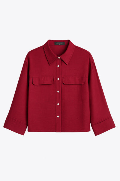 Camisa corta de fit oversized, manga 3/4 amplia con doblez en puños, cuello camisero, bolsillos frontales decorativos con cartera y pinza de amplitud en espalda. Cierre frontal con hilera de botones.