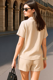 Camisa corta de lino, fit recto, manga corta, cuello camisero, bolsillo frontal de parche, bajo curveado con aberturas laterales y cierre frontal con hilera de botones.