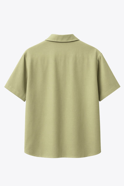 Camisa corta de lino, fit recto, manga corta, cuello camisero, bolsillo frontal de parche, bajo curveado con aberturas laterales y cierre frontal con hilera de botones.