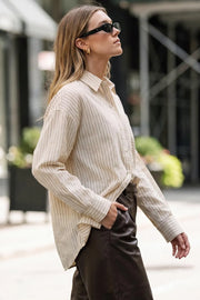 Camisa oversized de estampado rayas, manga larga con puño abotonado, cuello camisero, bajo curveado y cierre frontal con hilera de botones. Detalle de bolsillo frontal y pinza de amplitud en espalda.