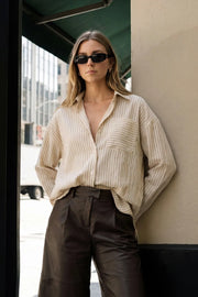 Camisa oversized de estampado rayas, manga larga con puño abotonado, cuello camisero, bajo curveado y cierre frontal con hilera de botones. Detalle de bolsillo frontal y pinza de amplitud en espalda.