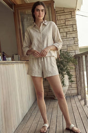 Camisa corta de rayas, ligeramente oversized, cuello camisero, manga larga rolled up con trabilla ajustable y botón. Cierre frontal con hilera de botones y detalle de pinza de amplitud en espalda.