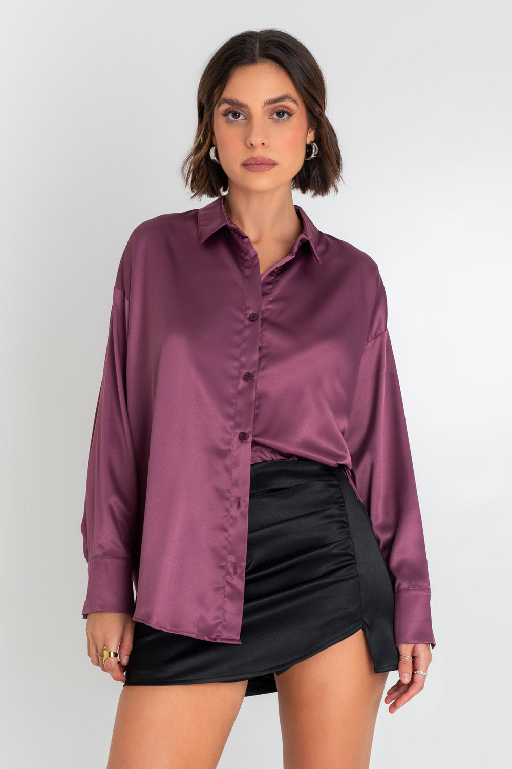 Camisa satinada de fit oversized, manga larga con puño abotonado, cuello camisero, bajo curveado, pinza de amplitud en espalda y cierre frontal con hilera de botones.