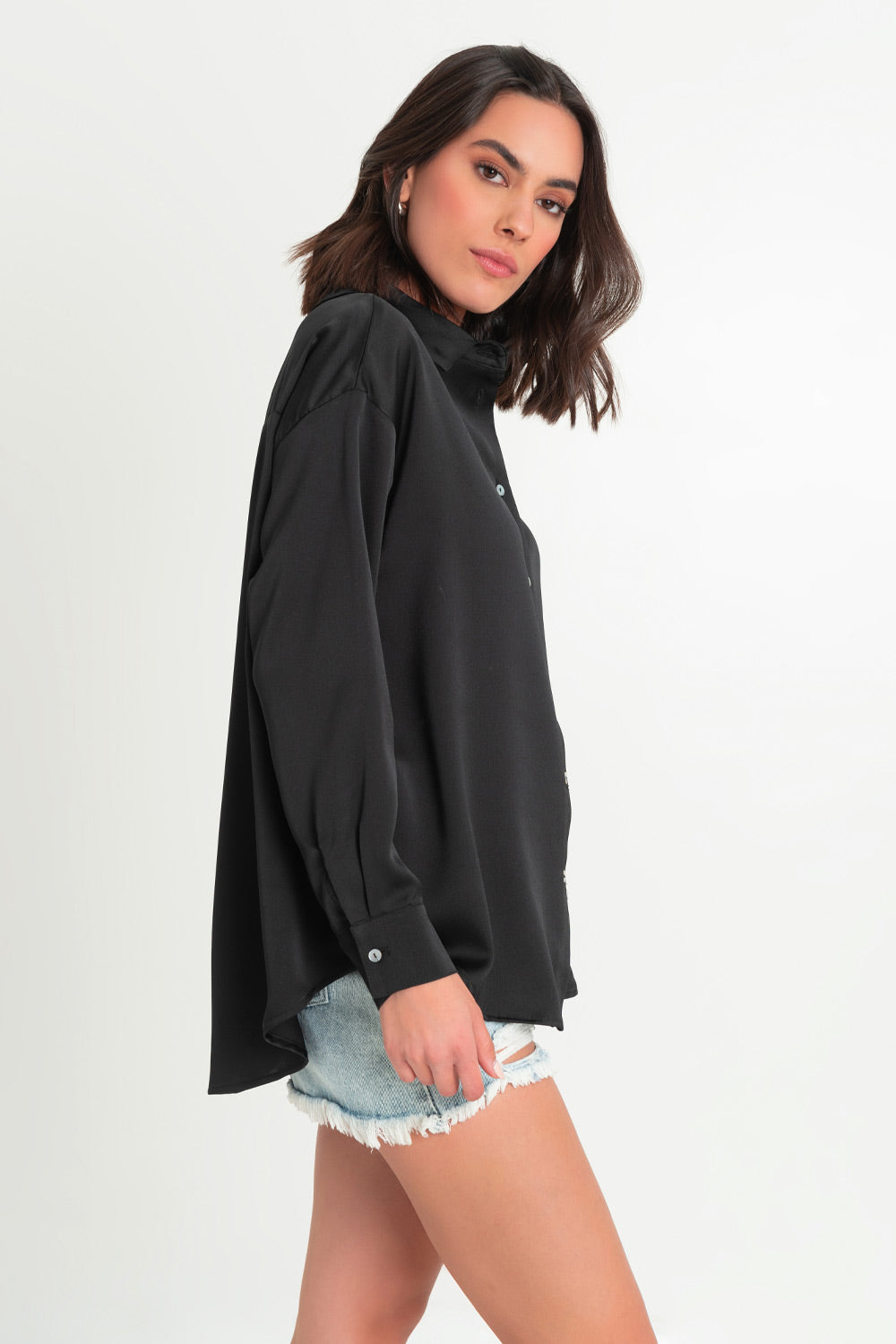 Camisa satinada de fit ligeramente oversized, manga larga con puño abotonado, cuello camisero, bajo curvado y cierre frontal con hilera de botones.