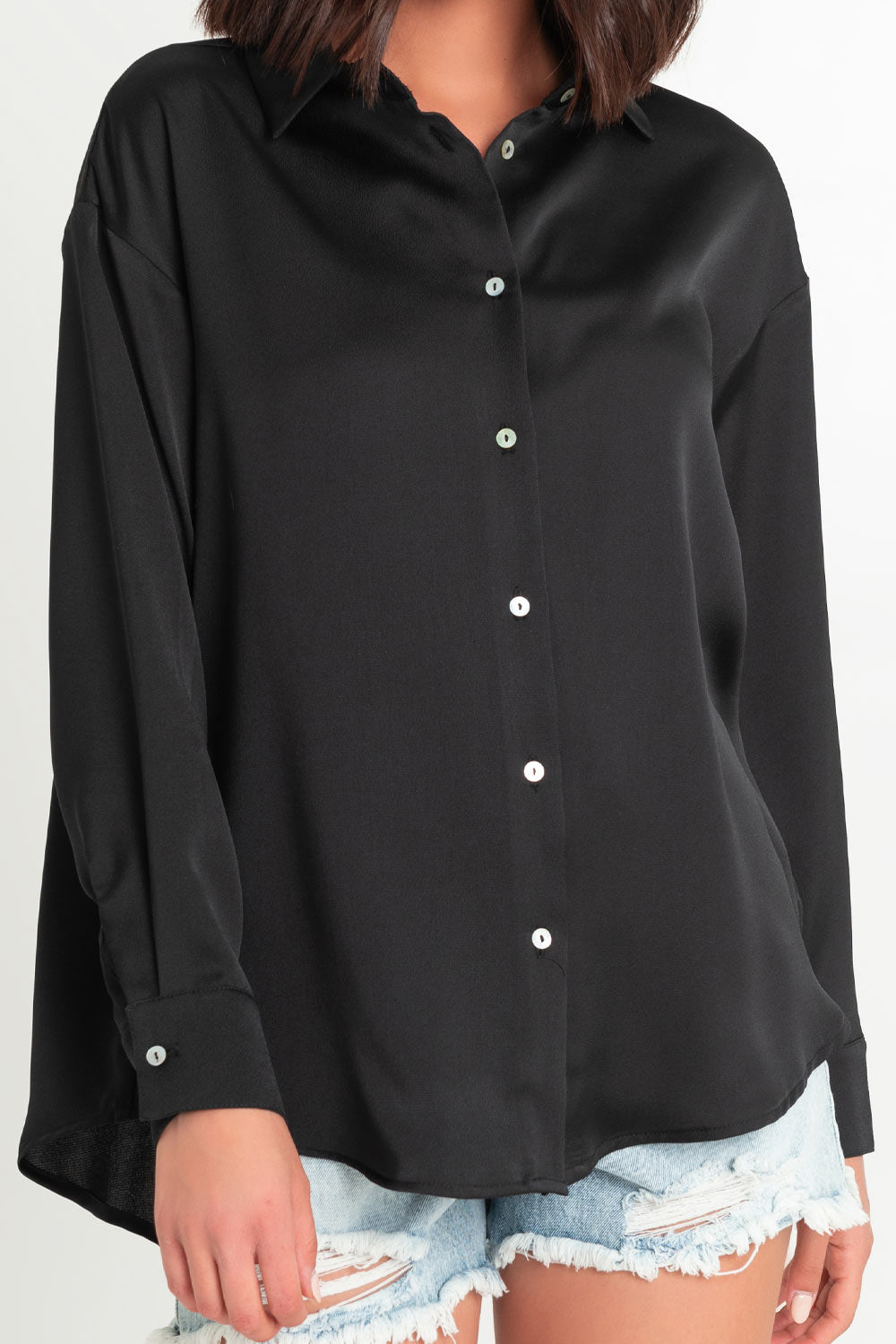 Camisa satinada de fit ligeramente oversized, manga larga con puño abotonado, cuello camisero, bajo curvado y cierre frontal con hilera de botones.