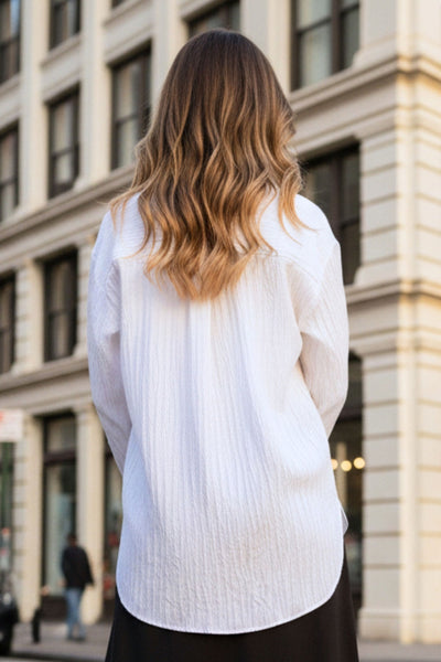 Camisa oversized de fit recto, manga larga con puño abotonado, cuello camisero, bajo curveado y cierre frontal con hilera de botones. Detalle de textura en tejido.