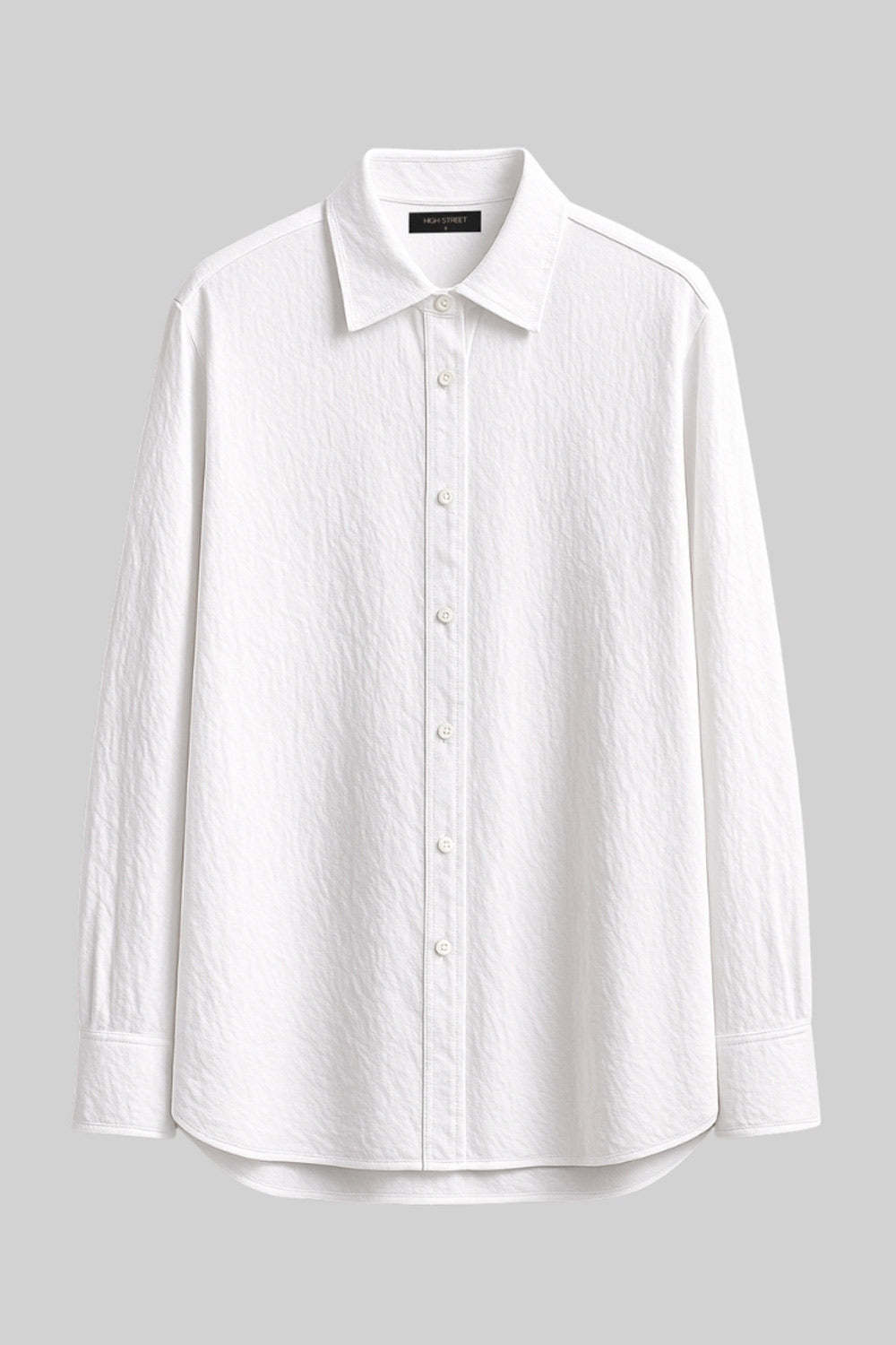 Camisa oversized de fit recto, manga larga con puño abotonado, cuello camisero, bajo curveado y cierre frontal con hilera de botones. Detalle de textura en tejido.