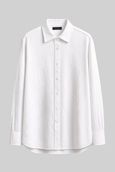 Camisa oversized de fit recto, manga larga con puño abotonado, cuello camisero, bajo curveado y cierre frontal con hilera de botones. Detalle de textura en tejido.