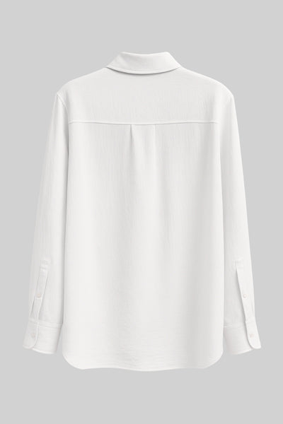 Camisa oversized de fit recto, manga larga con puño abotonado, cuello camisero, bajo curveado y cierre frontal con hilera de botones. Detalle de textura en tejido.