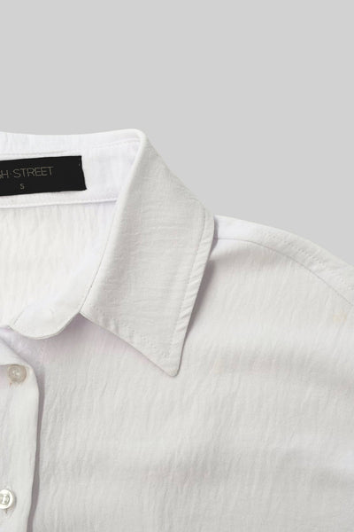 Camisa oversized de fit recto, manga larga con puño abotonado, cuello camisero, bajo curveado y cierre frontal con hilera de botones. Detalle de textura en tejido.