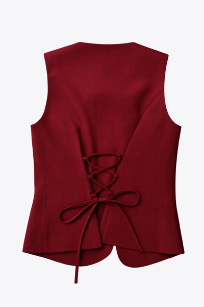 Chaleco ajustado de cuello redondo, pinzas frontales, fit recto, cierre frontal con hilera de botones en contraste, abertura frontal en bajo y lazado ajustable posterior.