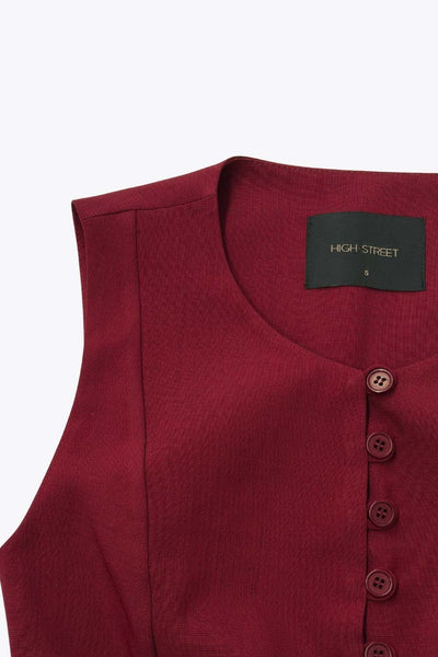 Chaleco ajustado de cuello redondo, pinzas frontales, fit recto, cierre frontal con hilera de botones en contraste, abertura frontal en bajo y lazado ajustable posterior.