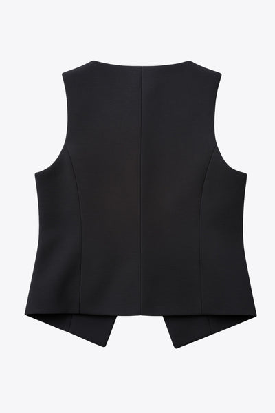 Chaleco corto de fit ajustado, cuello redondo, pinzas frontales, vivos decorativos y abertura frontal en bajo. Cierre frontal con hilera de botones en contraste.