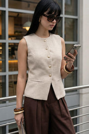 Chaleco de bouclé, fit ajustado, cuello redondo, vivos decorativos, pinzas frontales, cierre frontal con hilera de botones en contraste y abertura frontal v en bajo.