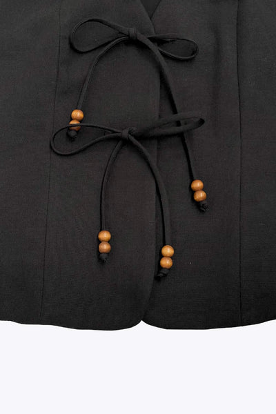 Chaleco de fit recto, pinzas frontales, escote v redondeado y cierre frontal de lazos amarrables con detalle en contraste.