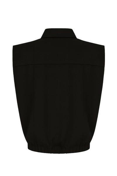 Chaleco corto de fit abullonado, con hombreras, cuello sport y cierre frontal con cremallera visible en contraste.