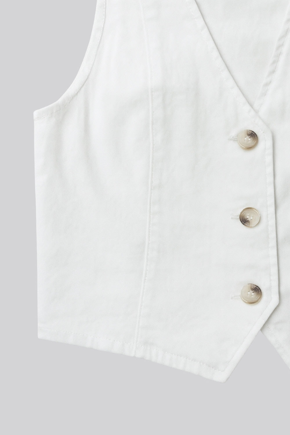 Chaleco corto de denim, fit ajustado, costuras frontales, escote v u y bajo v frontal. Cierre frontal con hilera de botones en contraste.