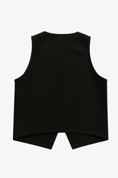 Chaleco corto de fit recto, cuello redondo y cierre frontal con hilera de botones en contraste. Detalle de abertura frontal en bajo.