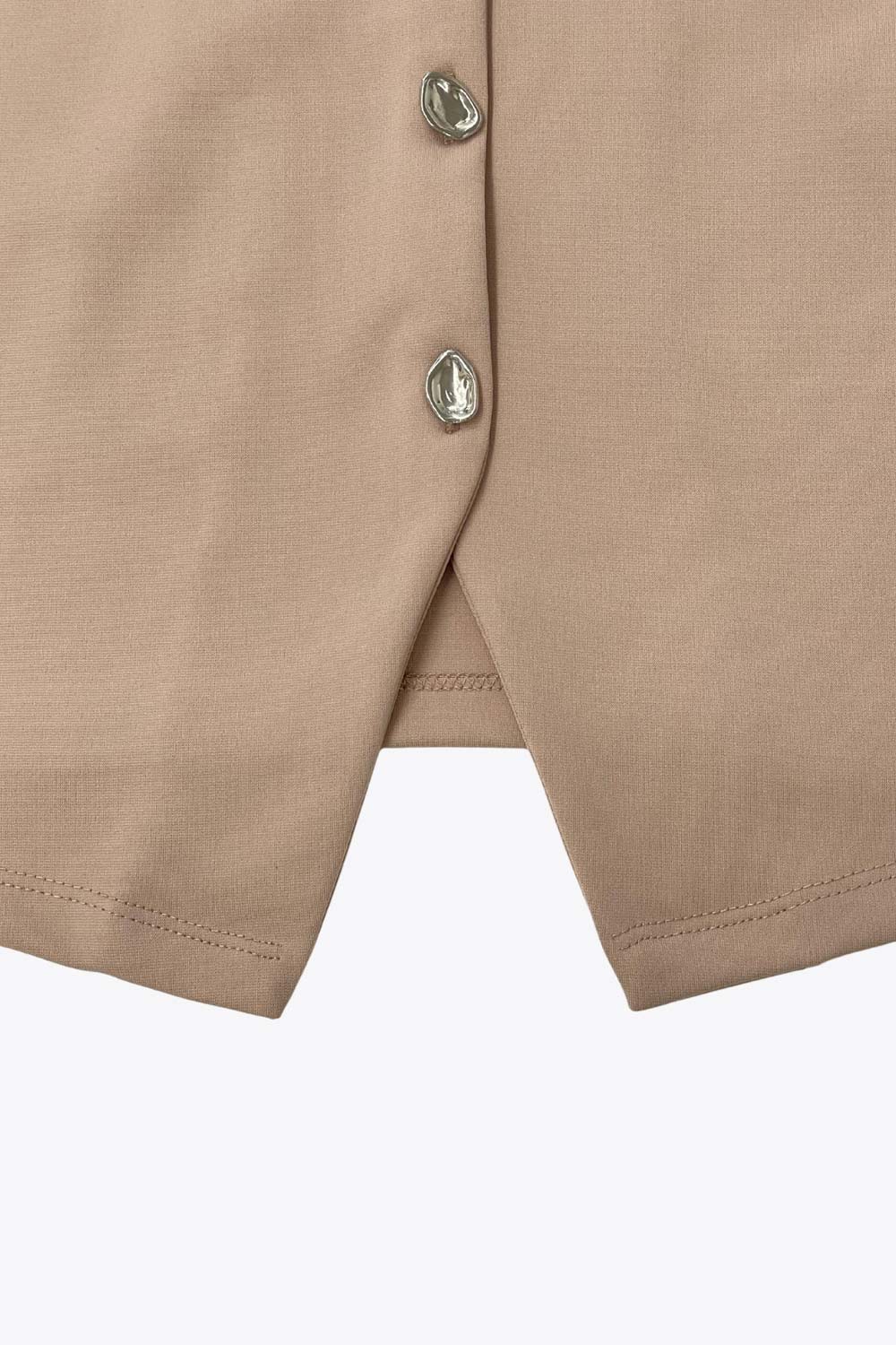 Chaleco corto de fit recto, cuello redondo y cierre frontal con hilera de botones en contraste. Detalle de abertura frontal en bajo.