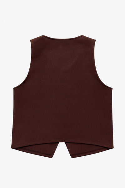 Chaleco corto de fit recto, cuello redondo y cierre frontal con hilera de botones en contraste. Detalle de abertura frontal en bajo.