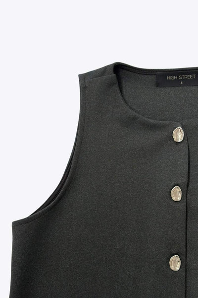 Chaleco corto de fit recto, cuello redondo y cierre frontal con hilera de botones en contraste. Detalle de abertura frontal en bajo.