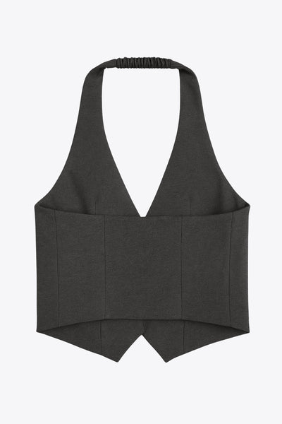 Chaleco corto cuello halter, fit ajustado, escote v, cierre frontal con hilera oculta de botones, vivos decorativos frontales y bajo v frontal. Escote en espalda y detalle de trabilla ajustable posterior.