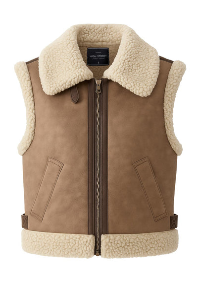 Chaleco corto de efecto piel, fit recto, cuello con solapa en contraste, bolsillos delanteros, trabillas laterales con hebillas en contraste y cierre frontal con cremallera. Detalle de borreguillo en contraste en interior, bordes y solapa.