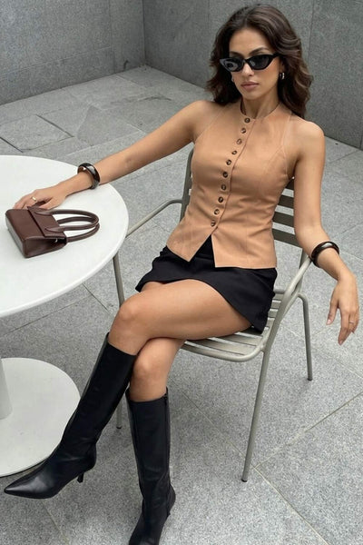 Chaleco corto halter, de fit ajustado, cuello redondo, cierre frontal con hilera oculta de botones, en contraste, pinzas frontales y abertura en bajo. Detalle de escote en espalda.