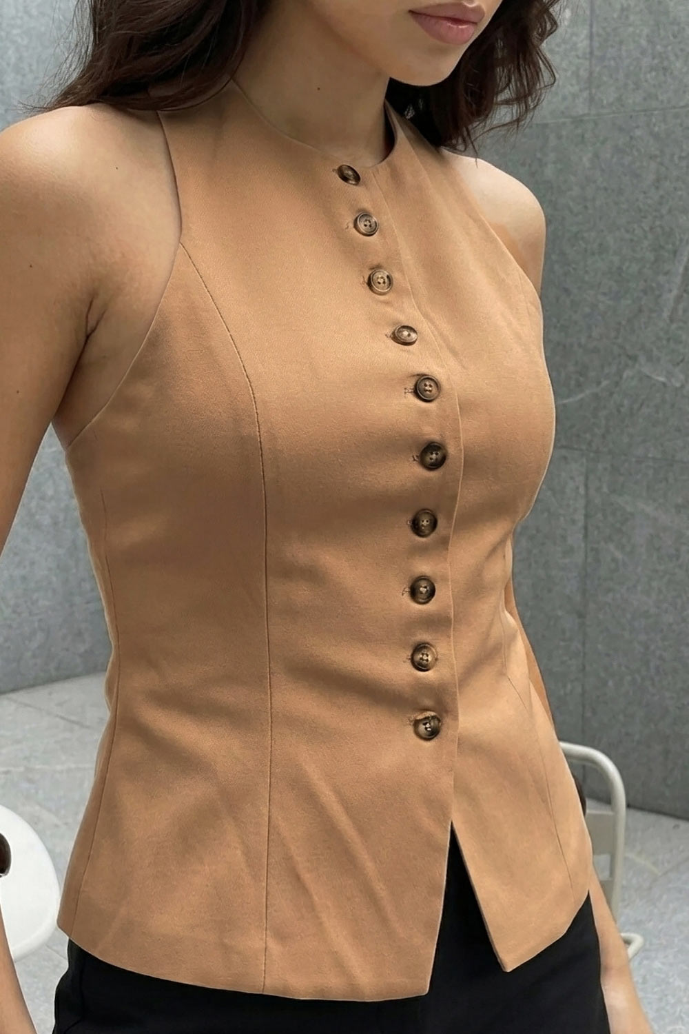 Chaleco corto halter, de fit ajustado, cuello redondo, cierre frontal con hilera oculta de botones, en contraste, pinzas frontales y abertura en bajo. Detalle de escote en espalda.