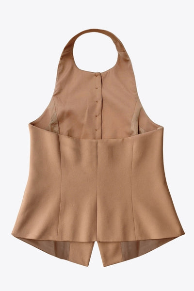 Chaleco corto halter, de fit ajustado, cuello redondo, cierre frontal con hilera oculta de botones, en contraste, pinzas frontales y abertura en bajo. Detalle de escote en espalda.