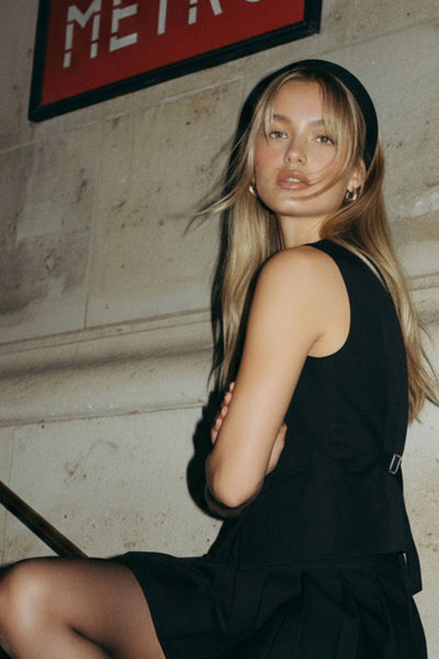 Chaleco ajustado con pinzas, cuello redondo, bajo v frontal con abertura y cierre con hilera de botones. Detalle de trabilla con hebilla posterior en contraste.