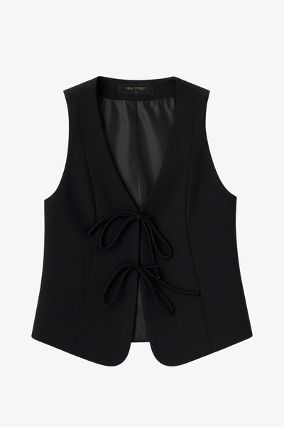 Chaleco de fit recto, cortes frontales, escote v redondeado y cierre frontal con lazos amarrables. Detalle de bajo curveado frontal.&nbsp;