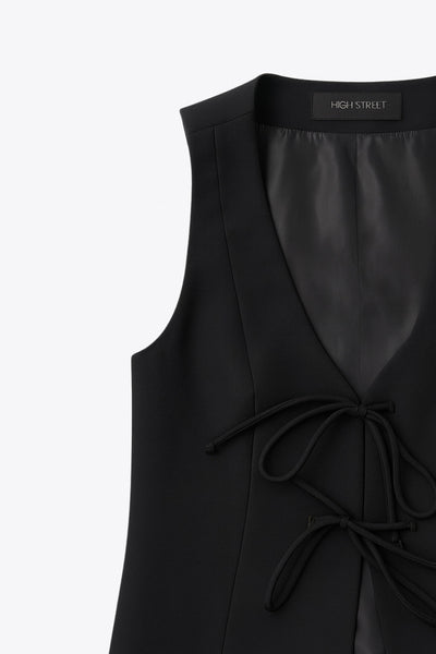 Chaleco de fit recto, cortes frontales, escote v redondeado y cierre frontal con lazos amarrables. Detalle de bajo curveado frontal.&nbsp;