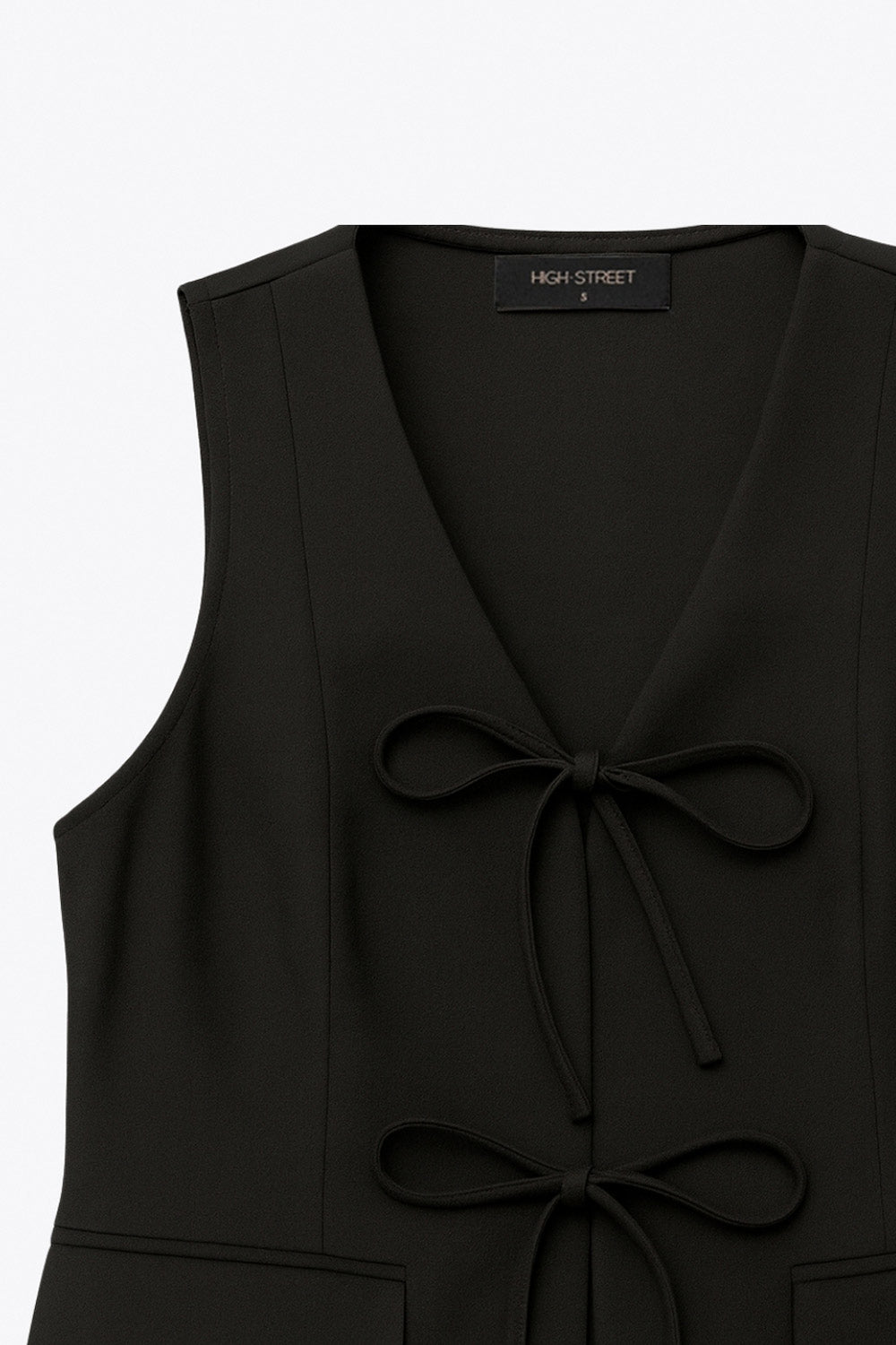 Chaleco de fit recto, escote v redondeado, pinzas frontales, bolsillos delanteros con cartera y cierre frontal con lazado amarrable.