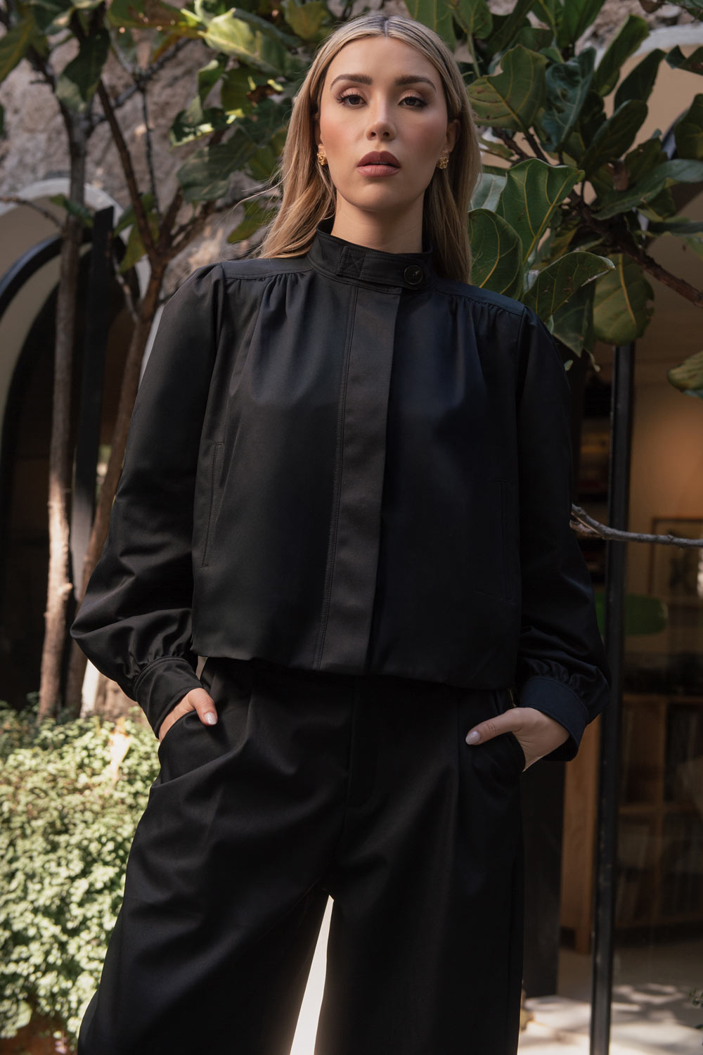 Chamarra corta de fit abullonado, cuello alto, manga larga abullonada con puño abotonado y cierre frontal con cremallera oculta. Detalle de plisados decorativos frontales y trabillas con botón en cuello.