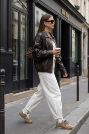 Chamarra de efecto piel, fit oversized, manga larga con puño abotonado, cuello solapa, bolsillos delanteros con vivos, costuras decorativas y elástico con plisados en bajo. Cierre frontal con cremallera oculta y botón.