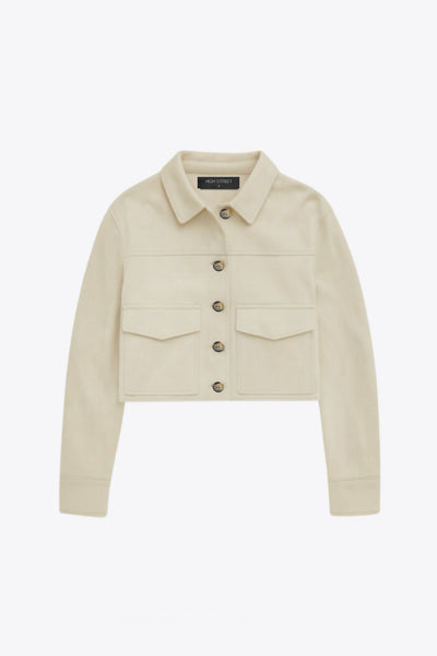 Chamarra corta fluida de gamuza, manga larga con puño abotonado, cuello camisero, bolsillos frontales de parche y cierre frontal con hilera de botones en contraste.