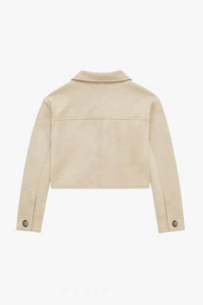 Chamarra corta fluida de gamuza, manga larga con puño abotonado, cuello camisero, bolsillos frontales de parche y cierre frontal con hilera de botones en contraste.